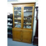 An early 20thC honey coloured oak cabinet bookcase,