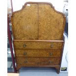 A mid 20thC burr walnut finished and mahogany cocktail cabinet with a pair of shaped doors,