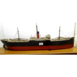 A scratch built clockwork model cargo vessel with a red and white hull and superstructure rigging