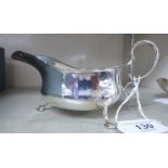 A silver sauce boat of shallow form with a double C-scrolled handle,