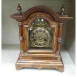 An early 20thC walnut cased mantel clock with a round arched top,