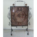 An early 20thC Arts & Crafts burnished, hammered copper and black painted, ornately wrought iron,