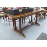 An early 20thC light oak dining table, raised on opposing slender,
