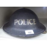 A World War II period painted metal police helmet (Please Note: this lot is offered subject to the