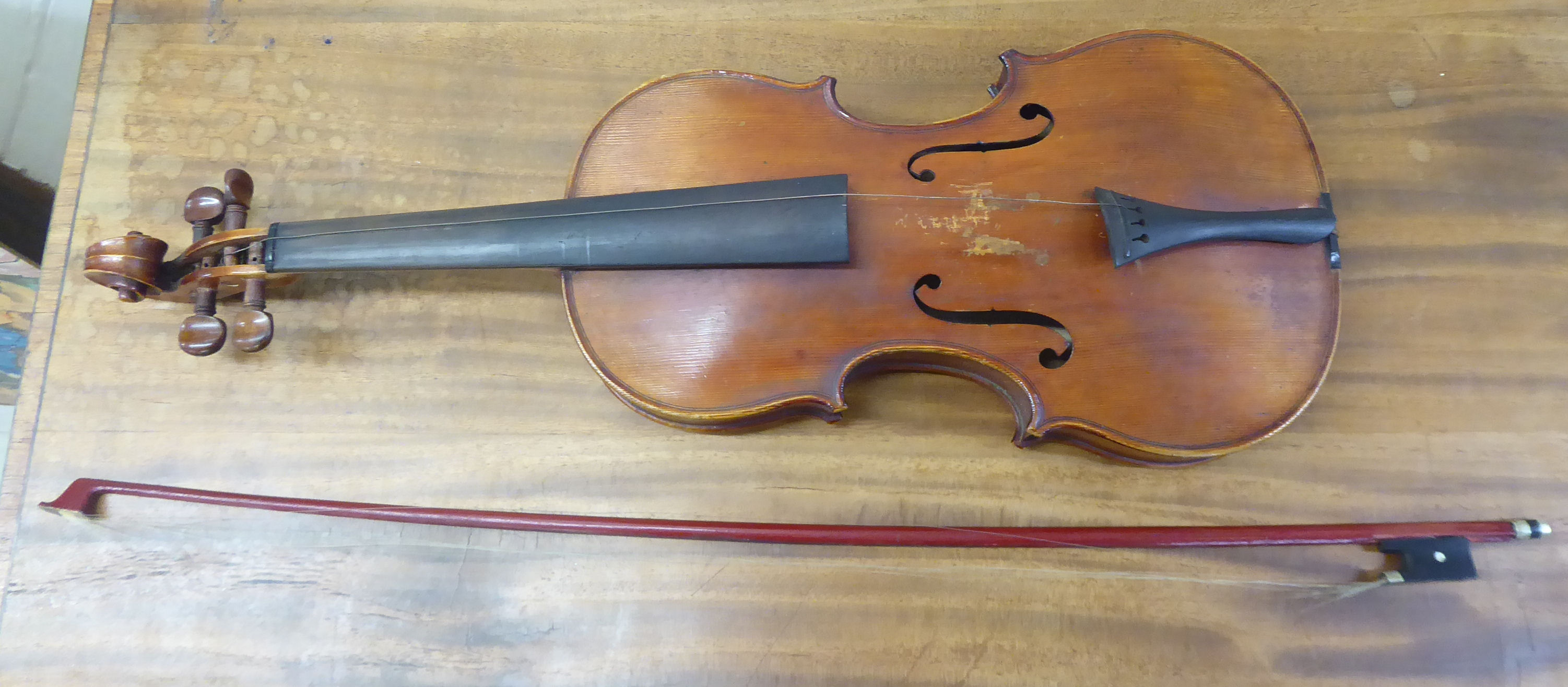 An early 20thC copy of an Antonius Stradivarius violin with a 14''L two piece back and a bow,