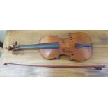 An early 20thC copy of an Antonius Stradivarius violin with a 14''L two piece back and a bow,