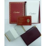 Two Cartier note pads and a burgundy coloured hide sleeve bears an identification card GL208753