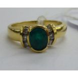 A gold coloured metal ring, set with an emerald,