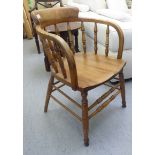 A mid 20thC stained beech framed Captain's chair with a turned, spindle back, arched swept arms,