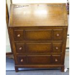 A 1930s oak bureau with a fall flap and three long drawers,