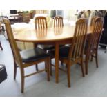 A 1970s teak finished extending oval dining table, raised on turned,