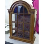 A 20thC walnut hanging display cabinet with a twelve section arched glazed door,
