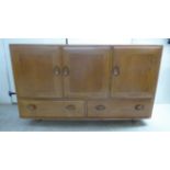 An Ercol elm sideboard with three doors, over two long drawers,