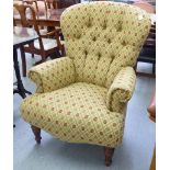 A modern button upholstered easy chair, raised on mahogany finished, turned,
