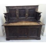 An 18thC and later, profusely carved, oak framed settle, the level back with lion carved arms,