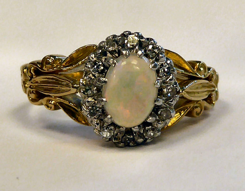 An 18ct gold ring, claw set with an opal, surrounded by diamonds,