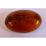 A white metal framed amber coloured brooch