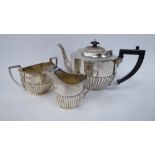 A three piece silver tea set of oval, demi-reeded form comprising a teapot with a S-shaped spout,