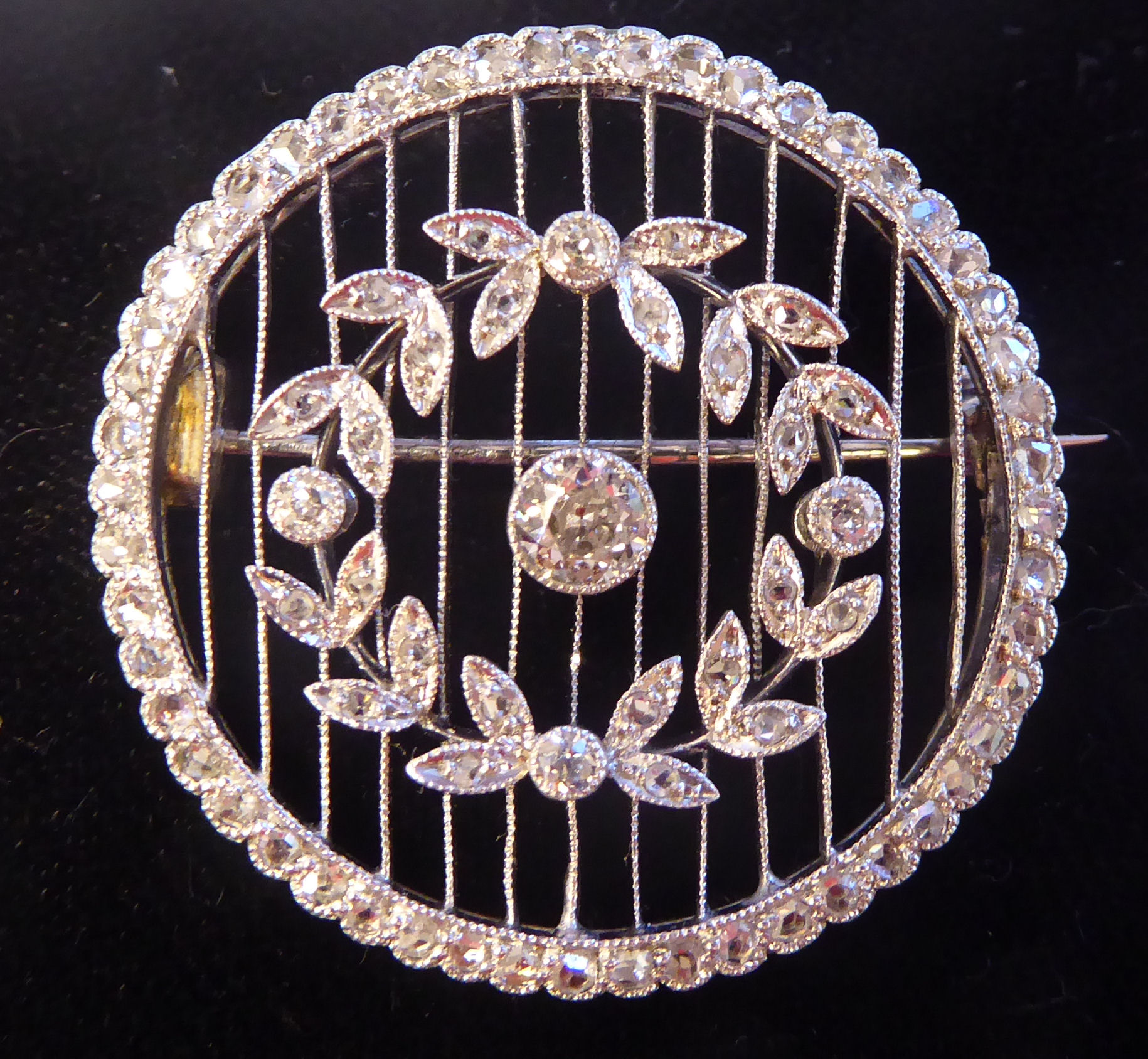 A white gold coloured metal and diamond set wheel brooch