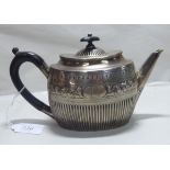 A Victorian silver teapot of oval demi-fluted form with an ebonised handle indistinct London marks