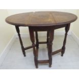 An early 20thC oak gateleg occasional table, the oval top with fall flaps,