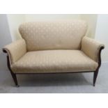 An Edwardian mahogany salon settee with a beige fabric upholstered back and seat, raised on square,