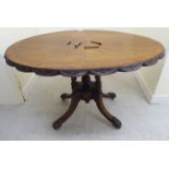 A late Victorian burr walnut and mahogany loo table, the oval top with a carved wavy edged border,