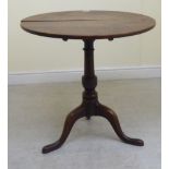 An early 19thC country made oak, tip-top pedestal table, the turned column raised on splayed,