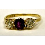 A gold coloured metal three stone ring, claw set with a ruby,