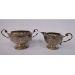A silver cream jug of shallow bowl design with a C-scrolled handle and pouring lip,