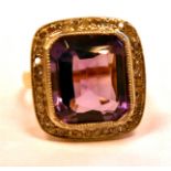 A gold coloured metal ring, set with an amethyst,