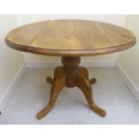 A modern honey coloured pine dropleaf table,