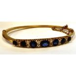A gold coloured metal hinged bangle, claw set with graduated sapphires and diamonds,