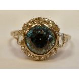 A white gold coloured metal ring, set with a blue zircon,