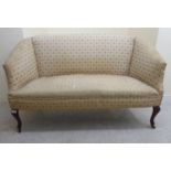 An Edwardian cottage two person settee, upholstered in patterned cream coloured fabric,