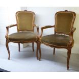 A pair of late 19thC Louis XVI design walnut framed salon chairs, each with a floral carved crest,