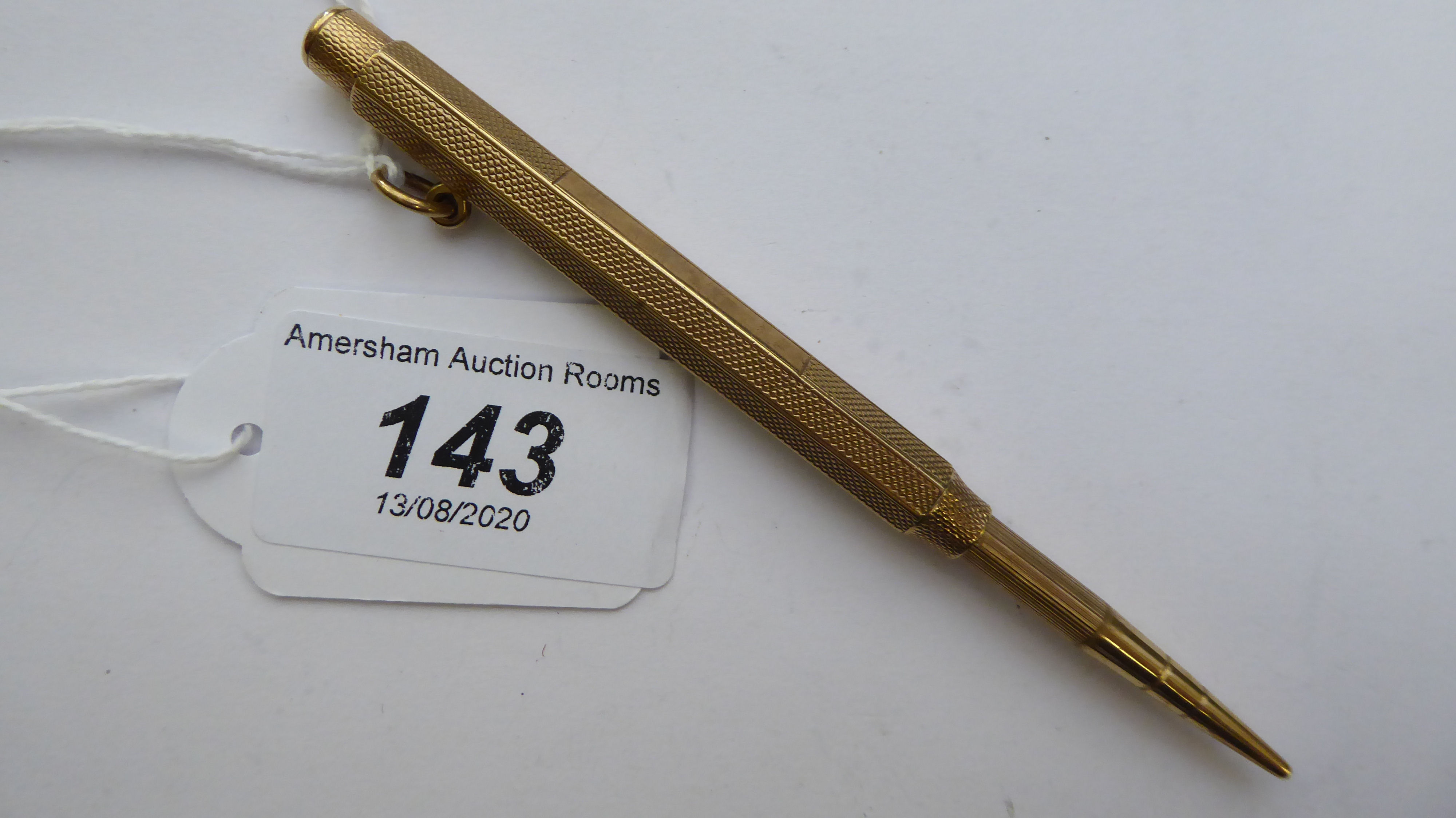 A 9ct gold cased polygon shaped propelling pencil with a press button terminal and pendant ring