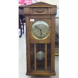 A 1930s light oak cased wall clock;