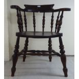 A 1920s dark stained oak and beech framed captain's chair, the solid seat raised on splayed,