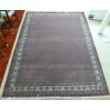 A modern woollen rug, decorated with a repeating border and stylised designs within,