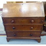 A George III oak bureau, the fall flap over three graduated drawers,