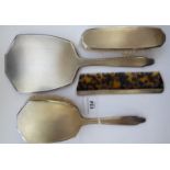 A four piece silver backed dressing table set, comprising a hand mirror, hair brush,