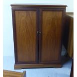 A modern teak finished cabinet, the pair of full-height doors enclosing a fitted interior,