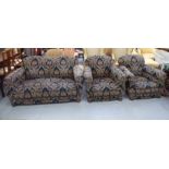 A 1930s three piece suite upholstered in an Art Nouveau fabric, raised on turned bun feet,