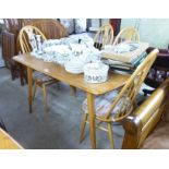 An Ercol pale coloured elm and beech dining table, the top having round corners, raised on splayed,