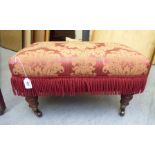 A Victorian style rectangular low stool, upholstered in tasselled, patterned maroon fabric,