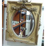 A late 19thC mirror, the oval bevelled plate set in an ornate gilt gesso frame,