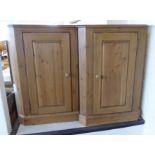 A pair of modern pine corner cupboards with a single panelled door,