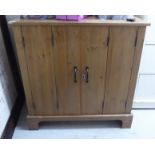 A modern pine cupboard with a pair of front folding doors,