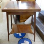 An Edwardian crossbanded, ebonised and string inlaid card table, the flame veneered, rotating,